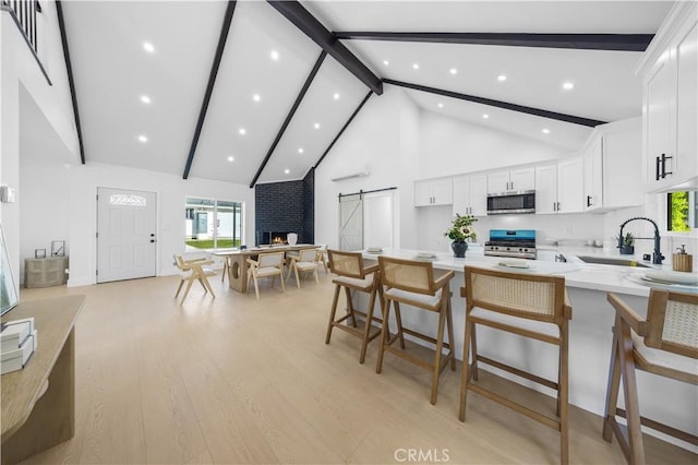 kitchen featuring a kitchen bar, white cabinetry, stainless steel appliances, a barn door, and kitchen peninsula