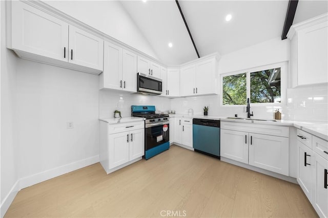 kitchen with sink, appliances with stainless steel finishes, white cabinets, and vaulted ceiling