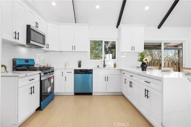 kitchen featuring sink, light stone counters, light wood-type flooring, stainless steel appliances, and white cabinets