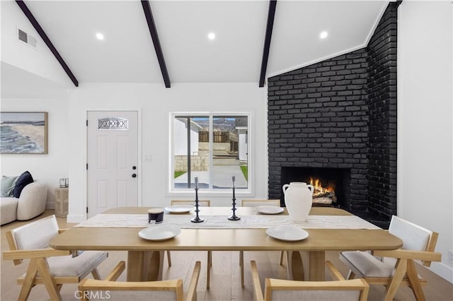 dining area featuring lofted ceiling with beams and a brick fireplace