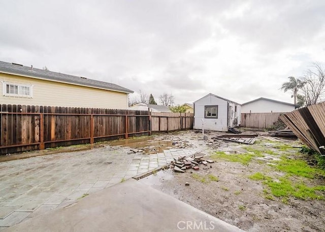 view of yard featuring a fenced backyard, an outdoor structure, and a patio area
