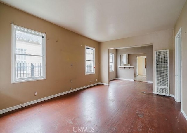 empty room with baseboards, wood finished floors, and a healthy amount of sunlight