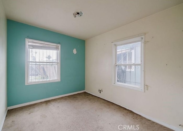 empty room featuring plenty of natural light, baseboards, and carpet floors
