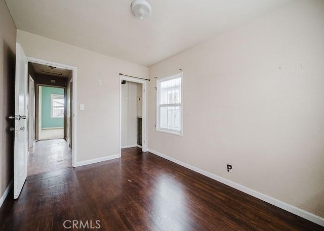 unfurnished bedroom featuring baseboards, wood finished floors, and a closet