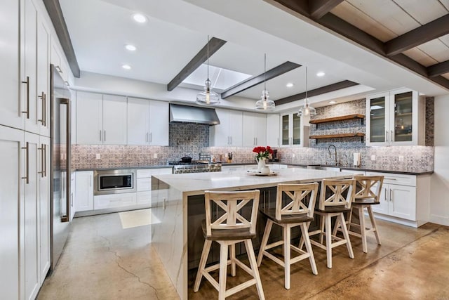 kitchen featuring stainless steel appliances, wall chimney range hood, a breakfast bar, a spacious island, and white cabinetry