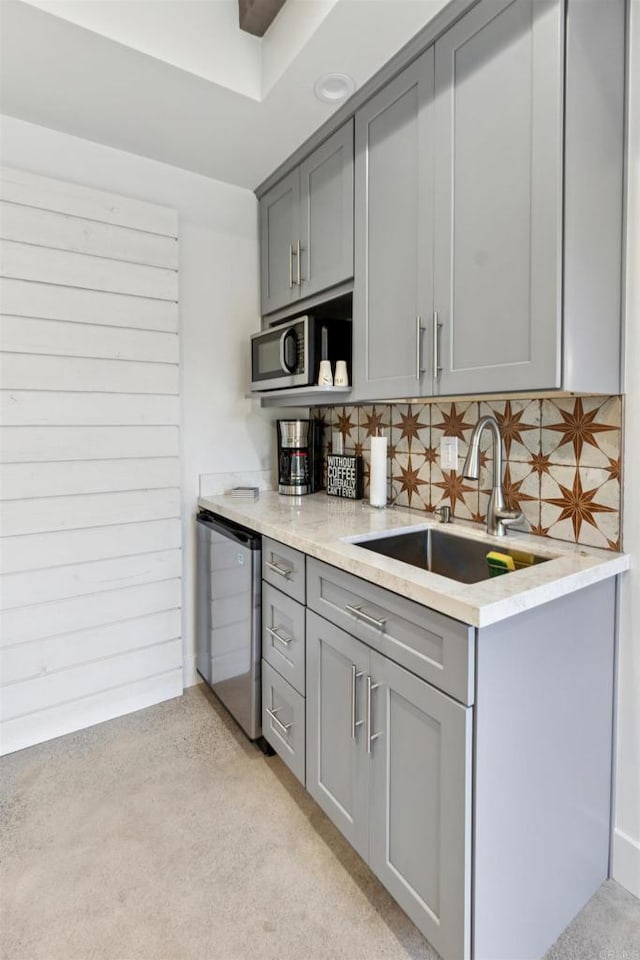 kitchen featuring stainless steel appliances, backsplash, gray cabinetry, and sink