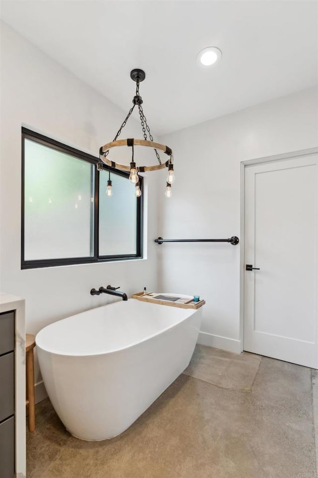 bathroom with a bathing tub, vanity, and concrete flooring