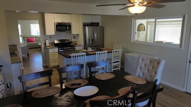 dining area with baseboards, ceiling fan, and light wood-style floors