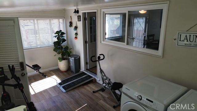 exercise area with dark wood-style floors, baseboards, and washer / clothes dryer