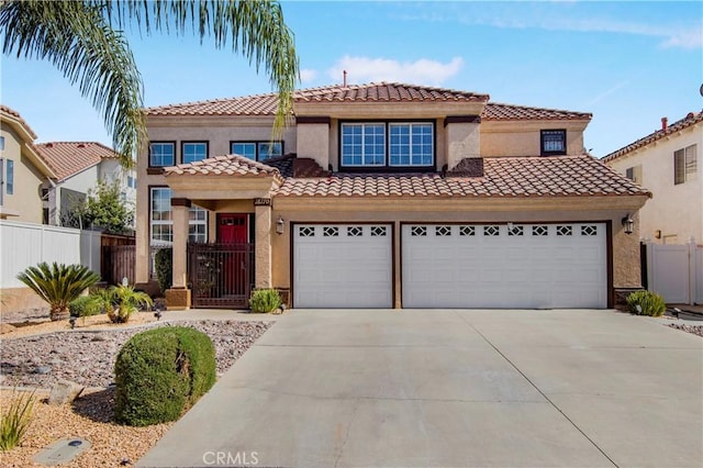 mediterranean / spanish-style house with driveway, a tiled roof, an attached garage, fence, and stucco siding