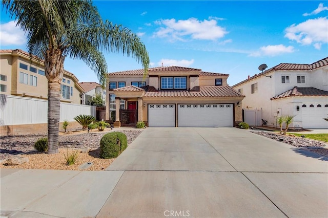 mediterranean / spanish house featuring concrete driveway, a tile roof, an attached garage, fence, and stucco siding