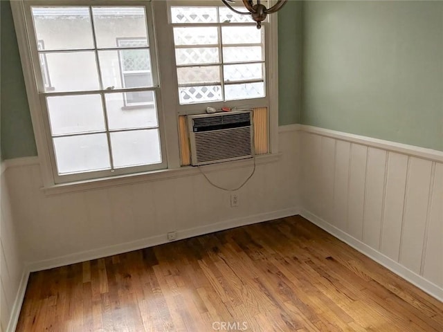 empty room with cooling unit, plenty of natural light, and wood-type flooring