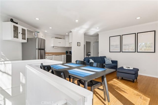 dining area with crown molding and light hardwood / wood-style flooring