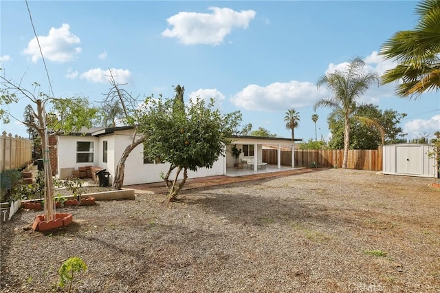 rear view of property with a storage shed and a patio area