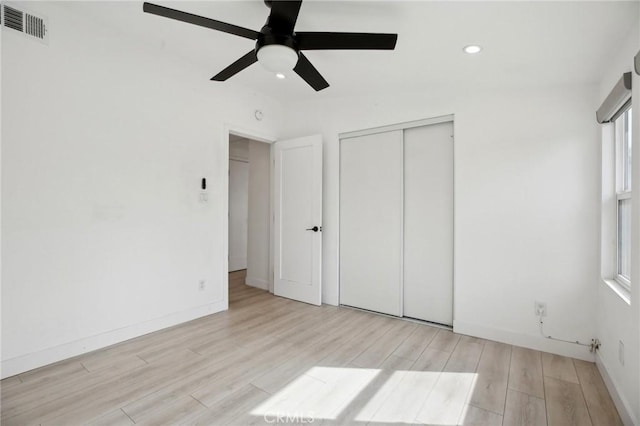 unfurnished bedroom with light wood-type flooring, a closet, and ceiling fan