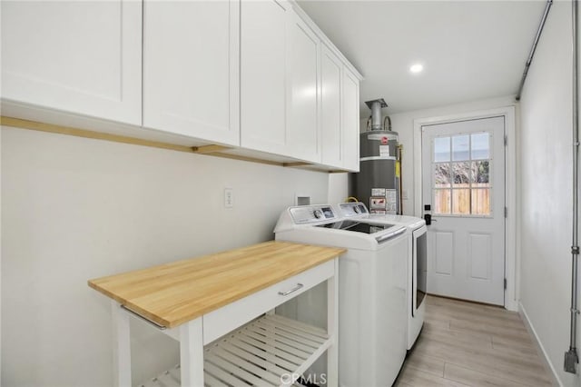 laundry area featuring cabinets, washing machine and dryer, gas water heater, and light hardwood / wood-style floors