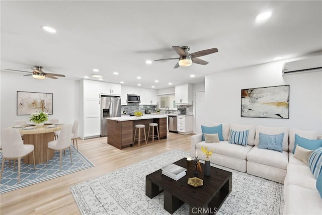 living room with ceiling fan, light hardwood / wood-style flooring, sink, and a wall unit AC