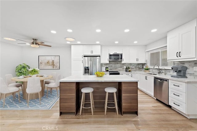 kitchen with backsplash, a kitchen island, white cabinets, and stainless steel appliances