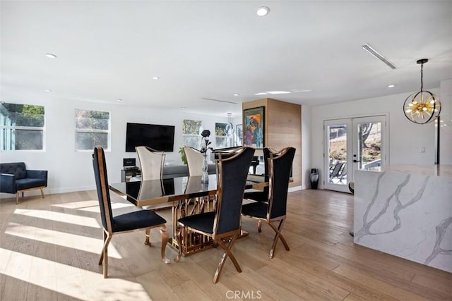 dining space featuring light wood-type flooring, an inviting chandelier, and french doors