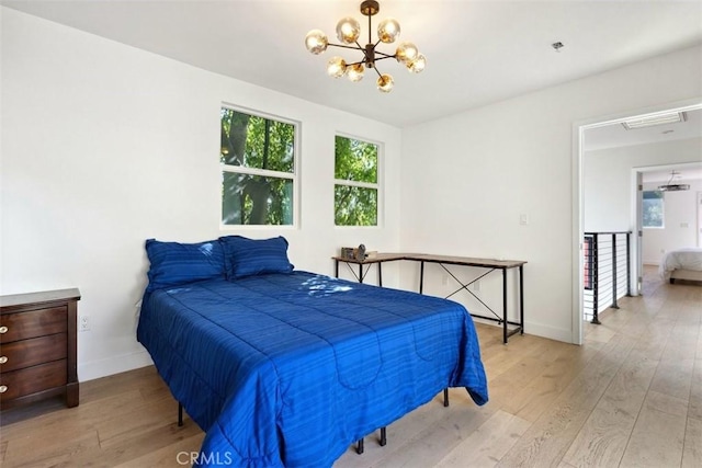 bedroom featuring light wood-type flooring and an inviting chandelier