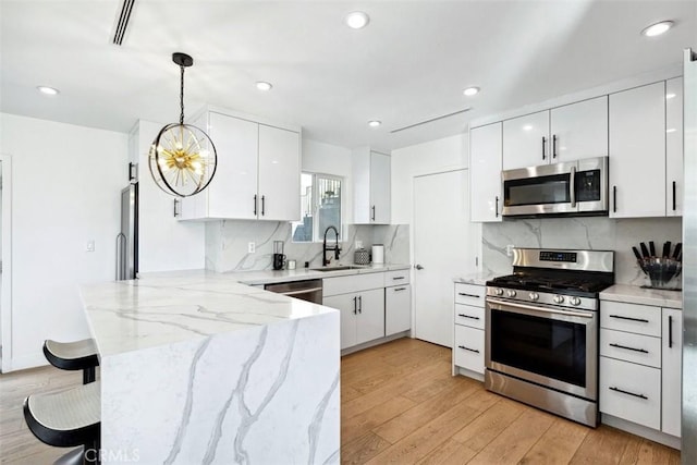 kitchen featuring white cabinetry, pendant lighting, stainless steel appliances, and sink