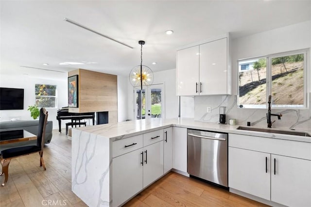 kitchen featuring white cabinetry, kitchen peninsula, hanging light fixtures, sink, and stainless steel dishwasher