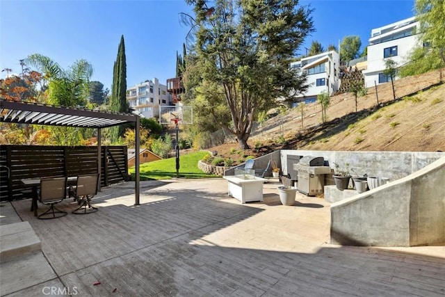 view of patio with area for grilling, a pergola, an outdoor fire pit, and a wooden deck