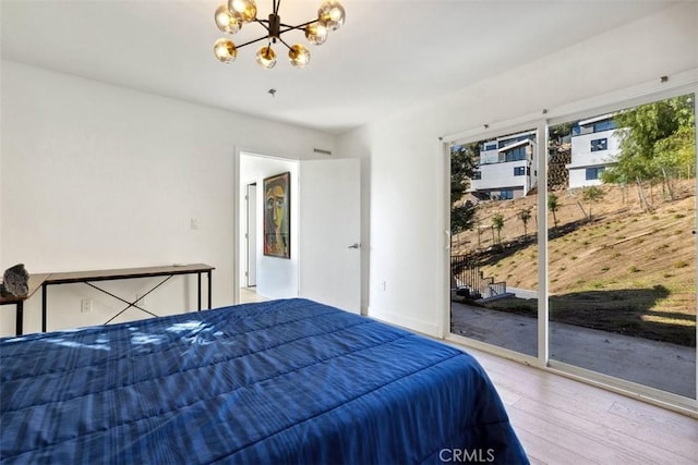 bedroom with an inviting chandelier, hardwood / wood-style flooring, and access to outside