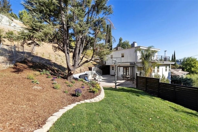 rear view of property featuring a yard, a patio, and a balcony