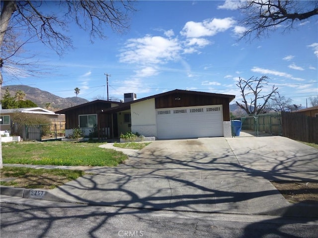 view of front of home with driveway, brick siding, an attached garage, and fence