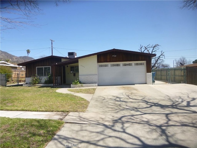 view of front facade with brick siding, fence, concrete driveway, a front yard, and a garage