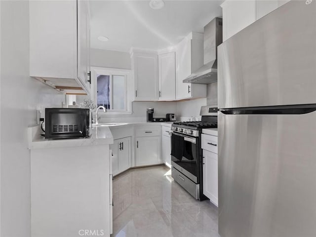 kitchen with stainless steel appliances, light countertops, white cabinets, a sink, and wall chimney exhaust hood