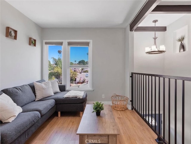 living area with light wood-type flooring, baseboards, and a chandelier