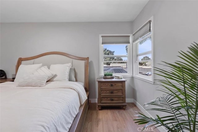 bedroom with light wood finished floors and baseboards