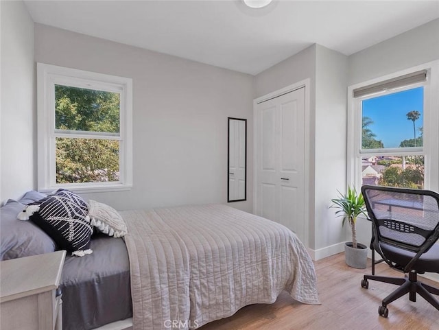 bedroom with baseboards, a closet, and light wood-style floors