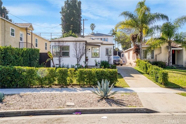 view of front facade with a residential view, fence, driveway, and stucco siding