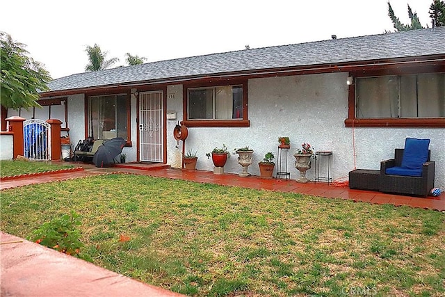 view of front facade featuring a front lawn, a shingled roof, and stucco siding