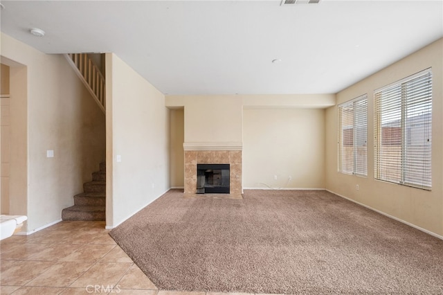 unfurnished living room featuring a tiled fireplace and light colored carpet