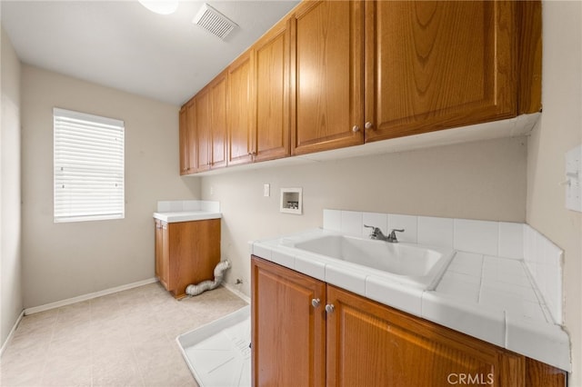 clothes washing area with sink, washer hookup, and cabinets