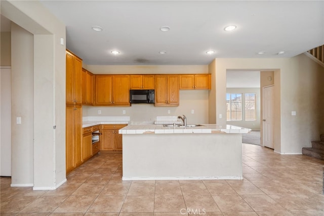 kitchen with an island with sink, light tile patterned floors, and sink