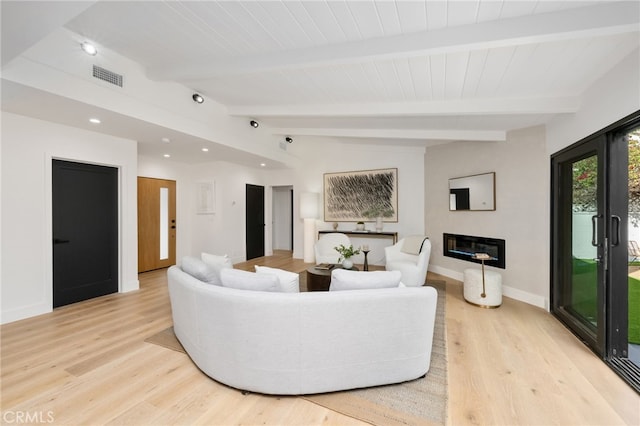 living area with vaulted ceiling with beams, light wood-style flooring, visible vents, and a glass covered fireplace