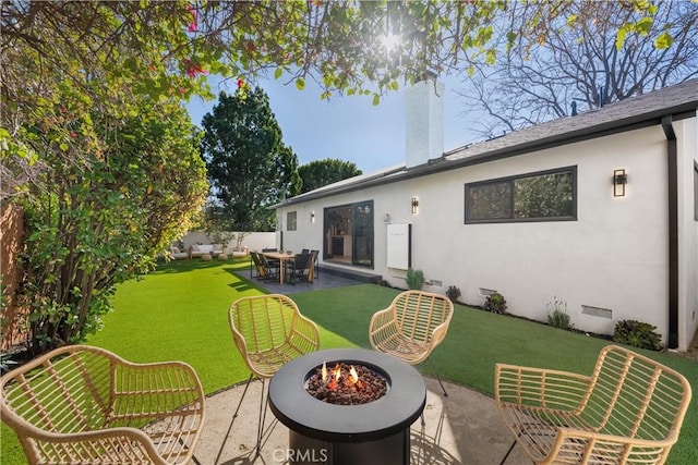 rear view of house featuring an outdoor fire pit, a yard, crawl space, stucco siding, and a chimney