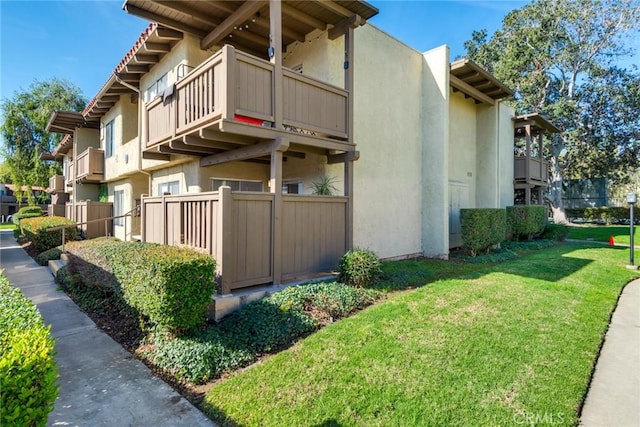 view of side of home with a yard and a balcony