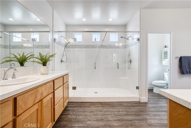 bathroom with vanity, walk in shower, toilet, and hardwood / wood-style floors