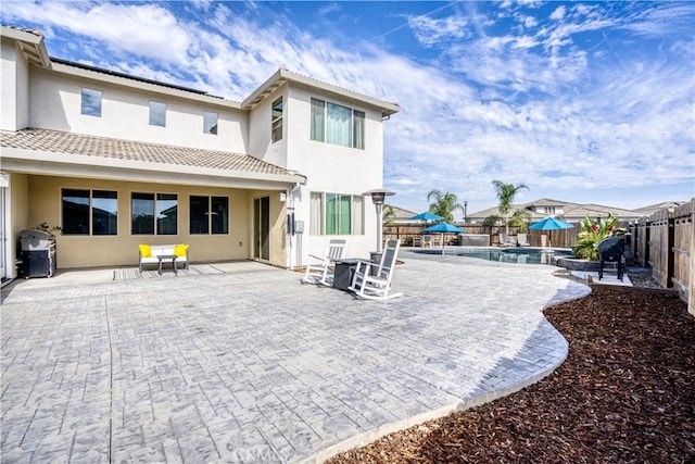 rear view of property featuring a patio area and a fenced in pool