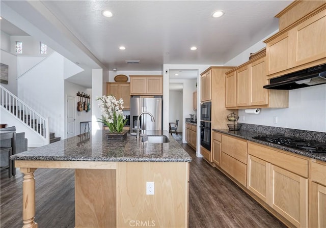 kitchen featuring a center island with sink, sink, light brown cabinetry, and black appliances