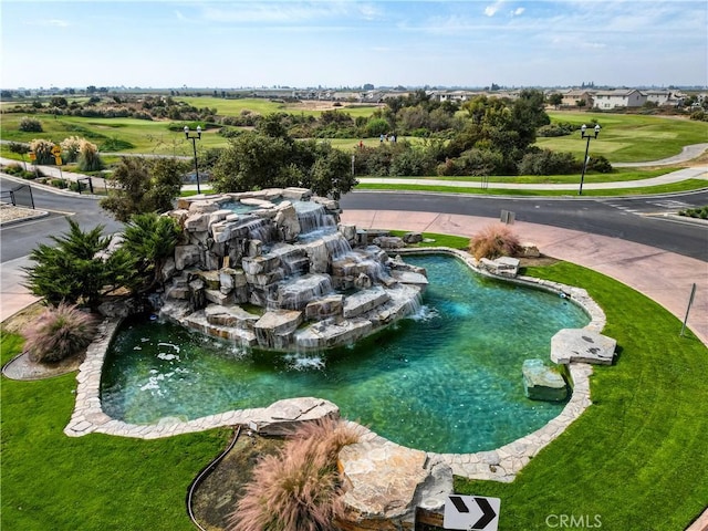 view of pool featuring pool water feature and a lawn