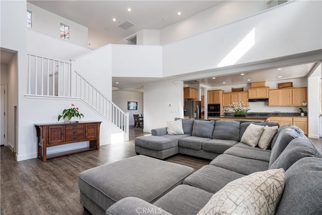 living room with dark hardwood / wood-style flooring and a towering ceiling