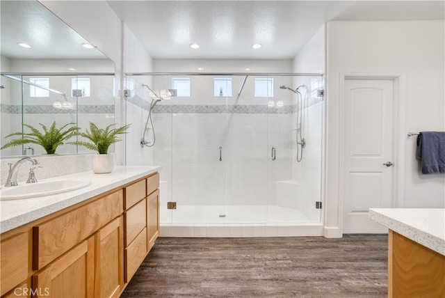 bathroom with vanity, a shower with shower door, and wood-type flooring