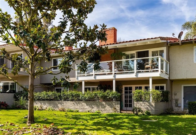 rear view of house with a chimney, stucco siding, and a lawn